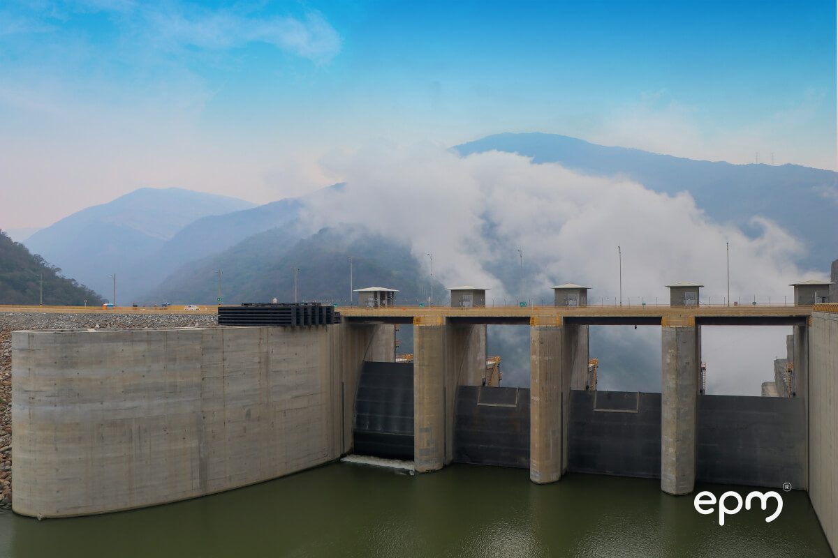 Fotografía de infraestructura hidroeléctrica de EPM en un entorno montañoso con cielo despejado y neblina.