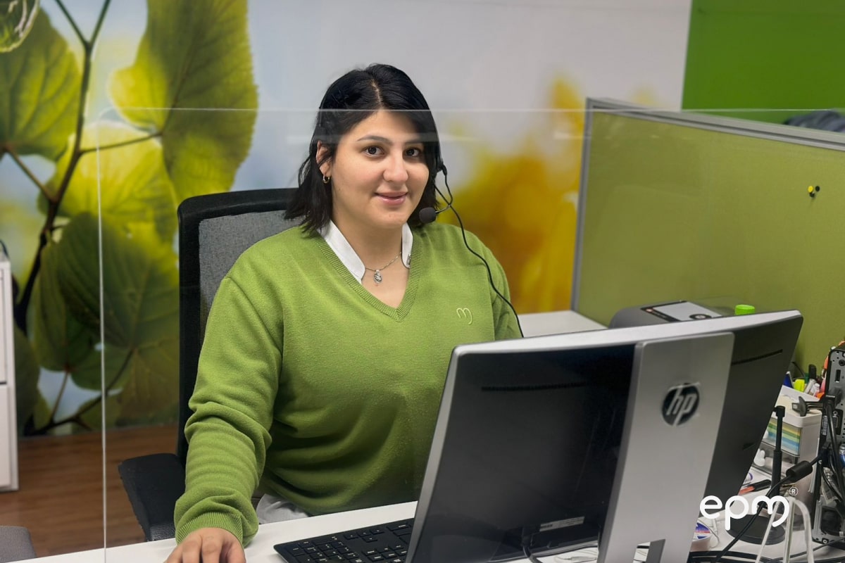 Mujer en oficina de EPM, trabajando en su computadora con auriculares.