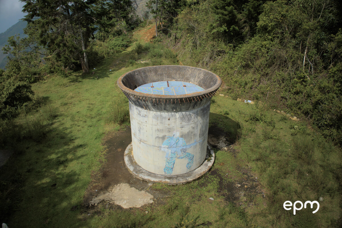 imagen de una estructura cilíndrica grande, posiblemente un tanque de agua, situada en un área con césped.