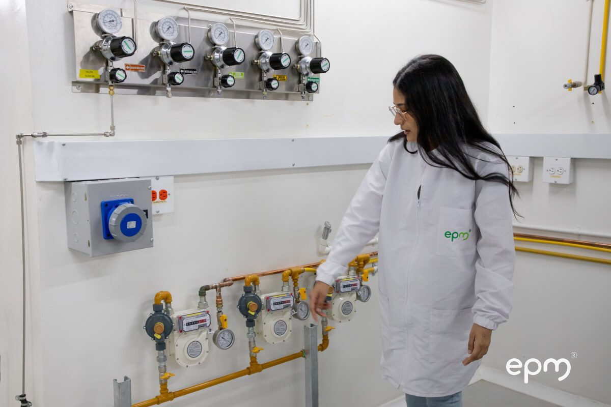 Fotografía de una mujer con bata de laboratorio de EPM ajustando válvulas y medidores de presión