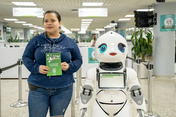 Fotografía de una persona al lado de ema (asistente virtual EPM)