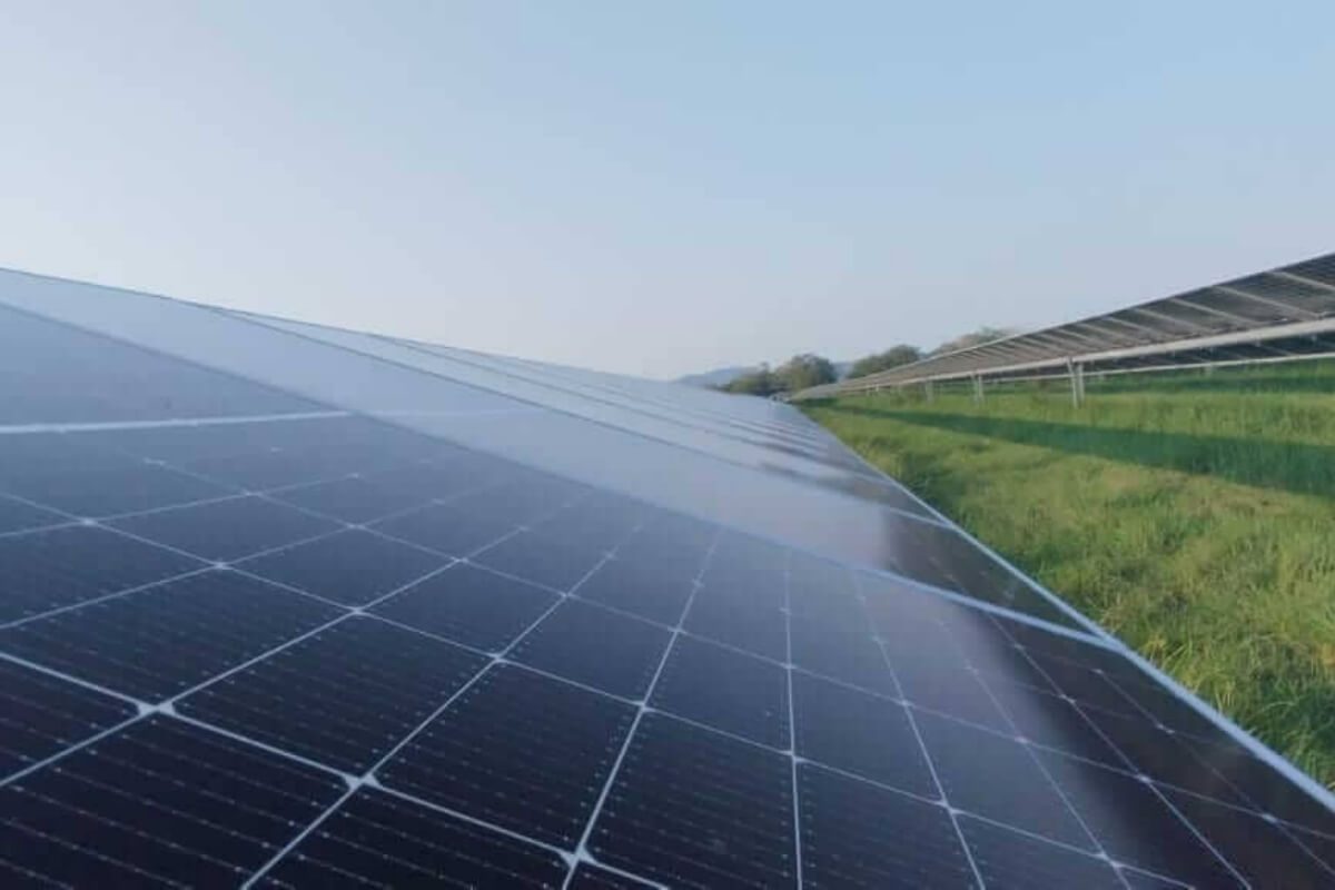 Fotografía de paneles solares instalados en un campo verde bajo un cielo despejado.