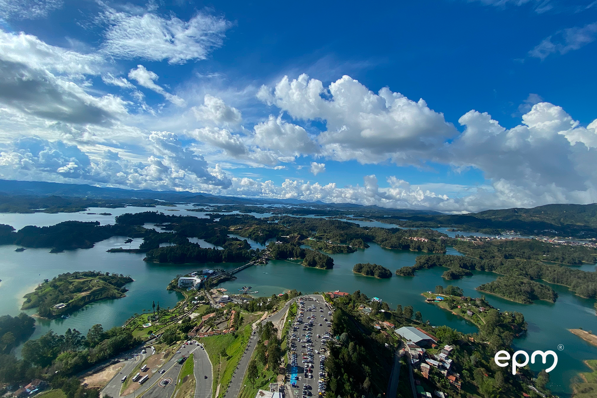 Fotografía panorámica del embalse de la represa de Guatapé. Al fondo se observa agua, casas y árboles