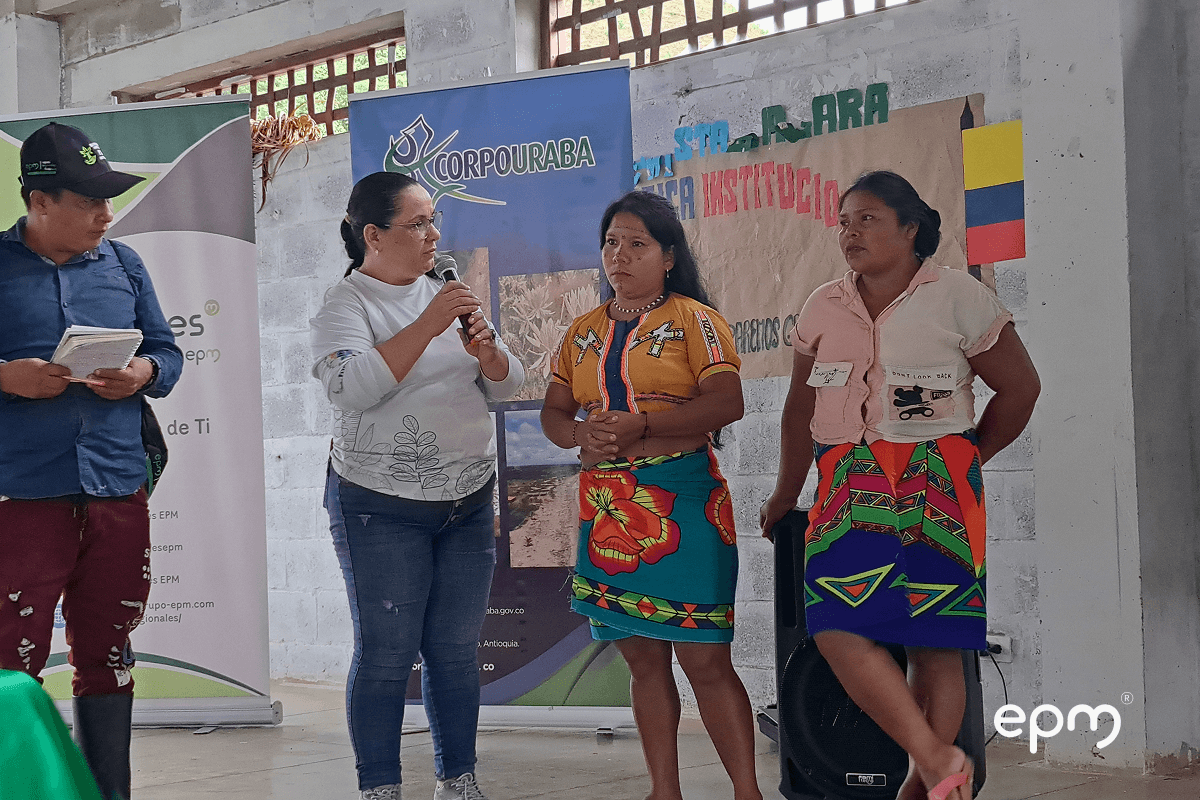 Fotografía de mujeres indígenas participan en un evento comunitario en un recinto cerrado.
