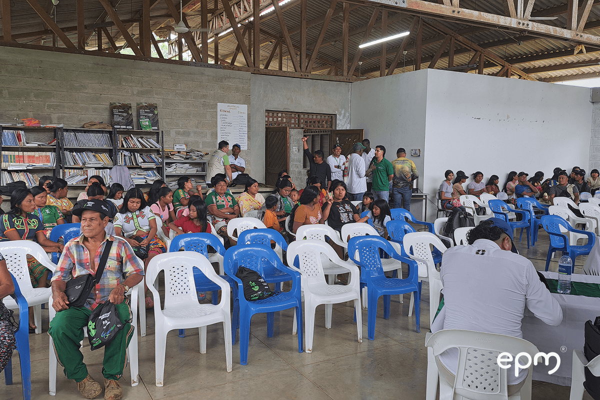 Fotografía de una reunión comunitaria en un salón amplio con techo de madera