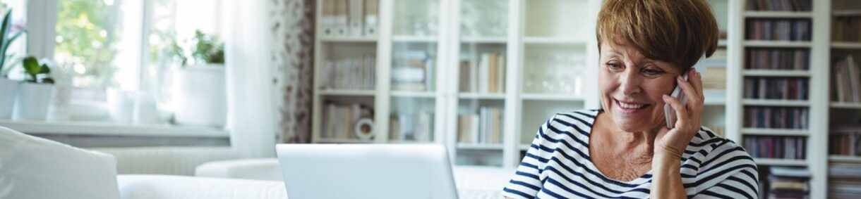 Mujer mayor sonriente hablando por teléfono en un entorno hogareño