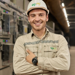 Trabajador de EPM con casco y uniforme de seguridad sonriendo en planta eléctrica