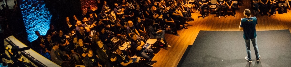 Hombre de pie en un escenario hablando frente a una audiencia en un auditorio. A la izquierda, texto sobre las Vinculaciones Publicitarias de EPM, que explican el apoyo a eventos de otras entidades con fines de bienestar social a cambio de beneficios publicitarios. Botón 'Ver vinculaciones'