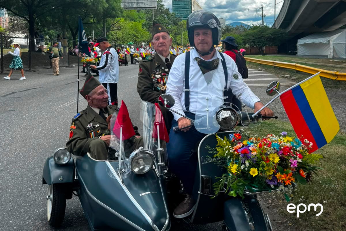 Participantes del Desfile de Autos Clásicos recorren Medellín en una motocicleta antigua decorada.