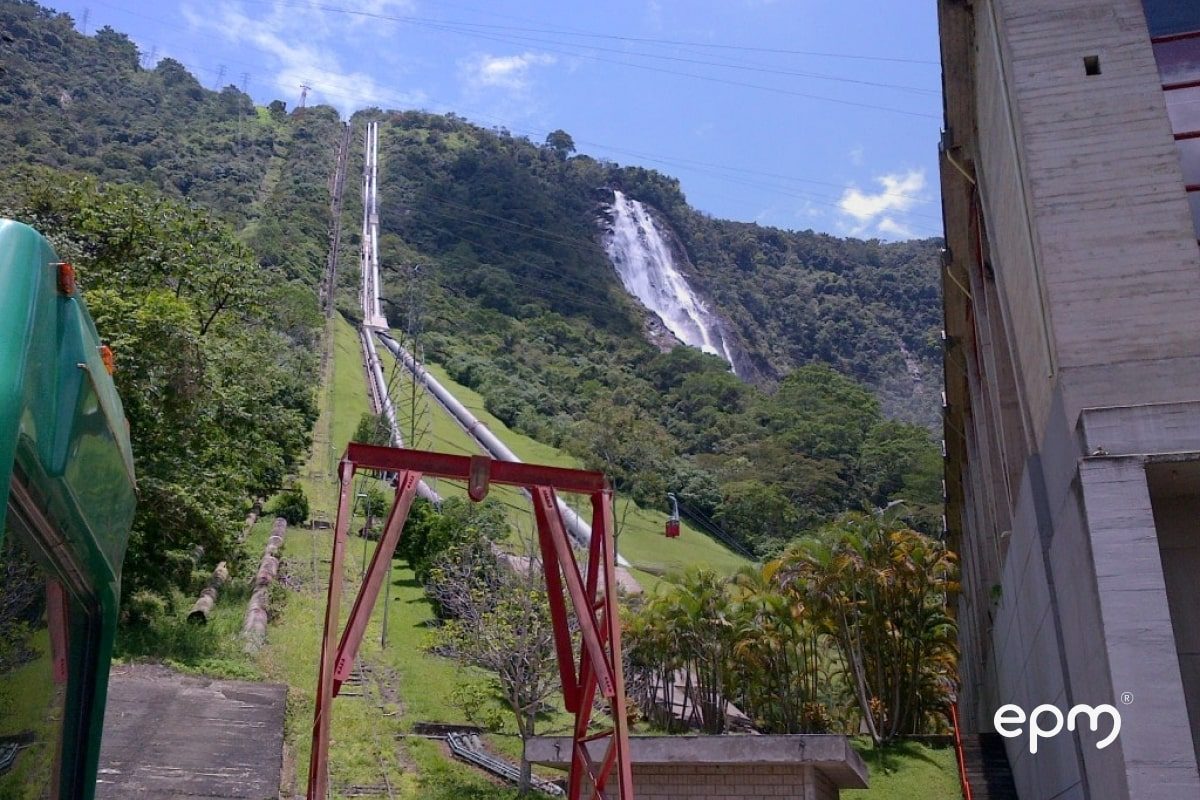 Photograph of a hydroelectric power plant located in a mountainous and green area.