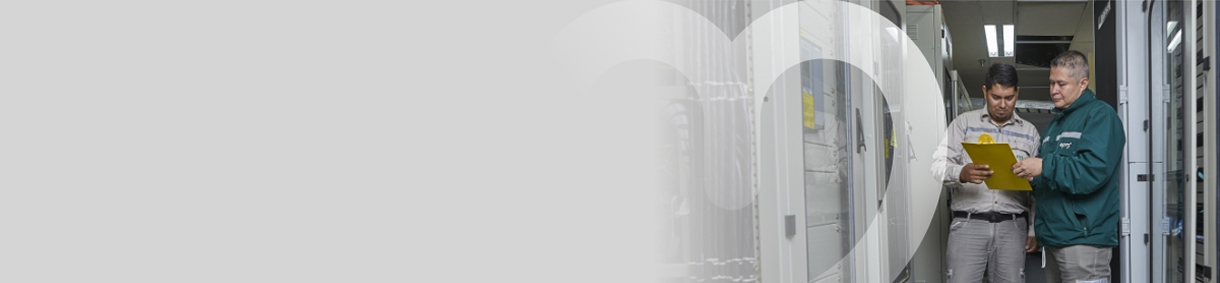 Dos trabajadores revisando documentos en una sala de servidores